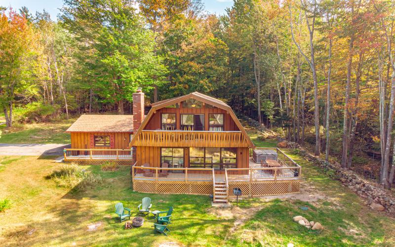 Exterior view of the ADK Whiteface Chalet featuring two levels with balcony, porch and patio by garage.