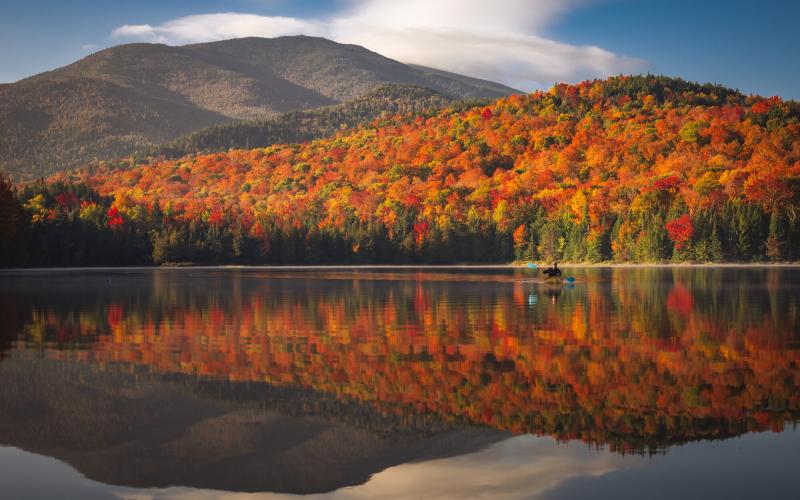 Fall view of a pond reflecting trees and mountains