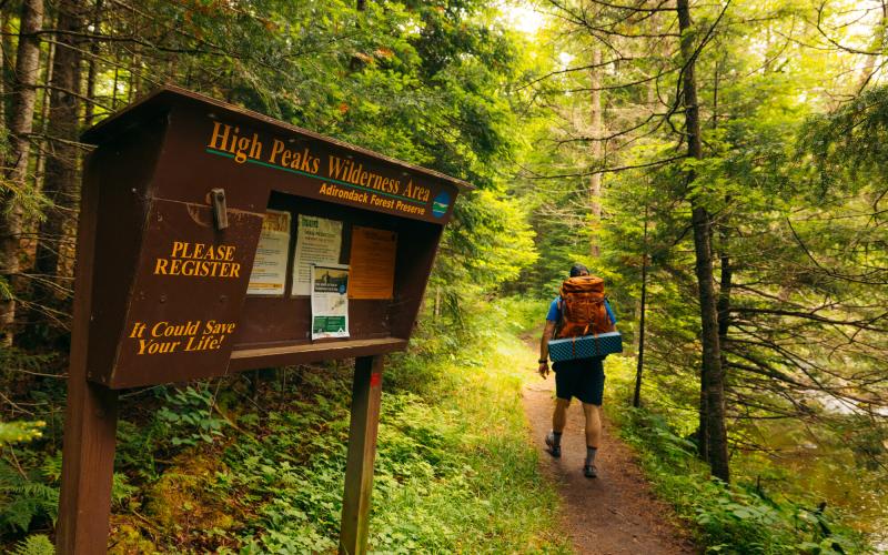 A hiker walking into the woods from a register box