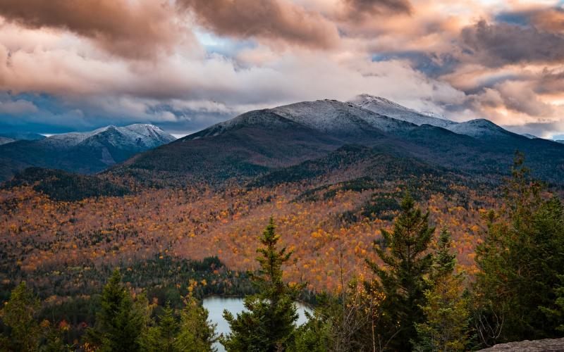 A pond and mountains with some snow on top during the late fall