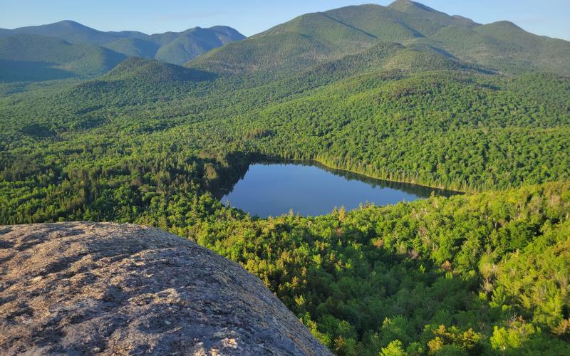 A small pond in front of tall mountains