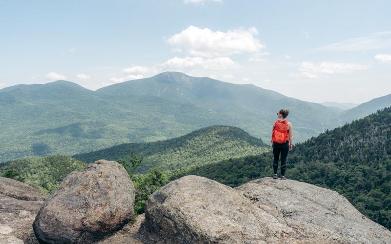 Hiker with red backpack at Rooster Comb summit