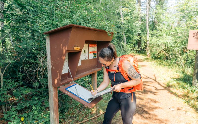 Hiker signs in at Rooster Comb trail register