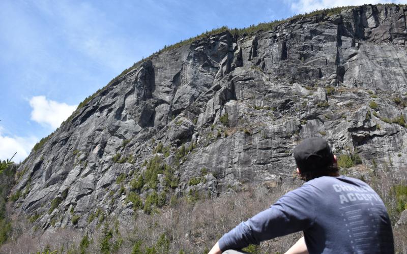 A hiker looking upo at a large rocky cliff