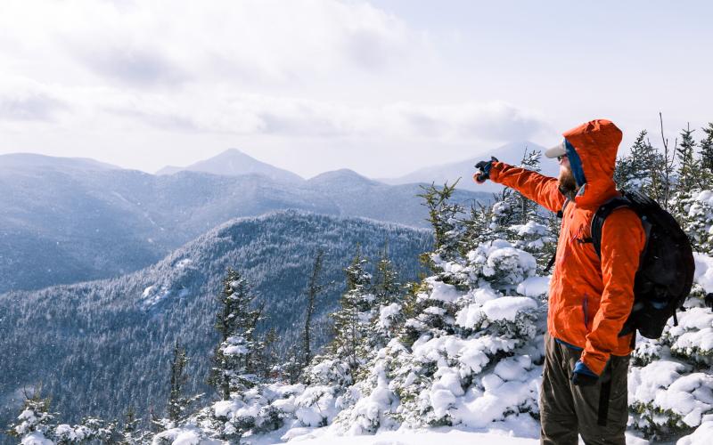 A guy points to other mountains from the top of Big Slide