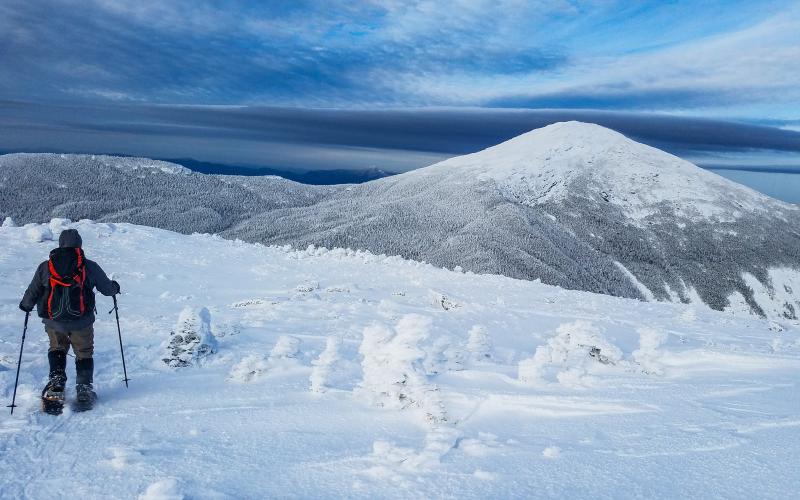 A snowshoer on a high alpine peak in the winter