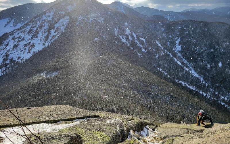 A hiker ascends a cliff in the mountains