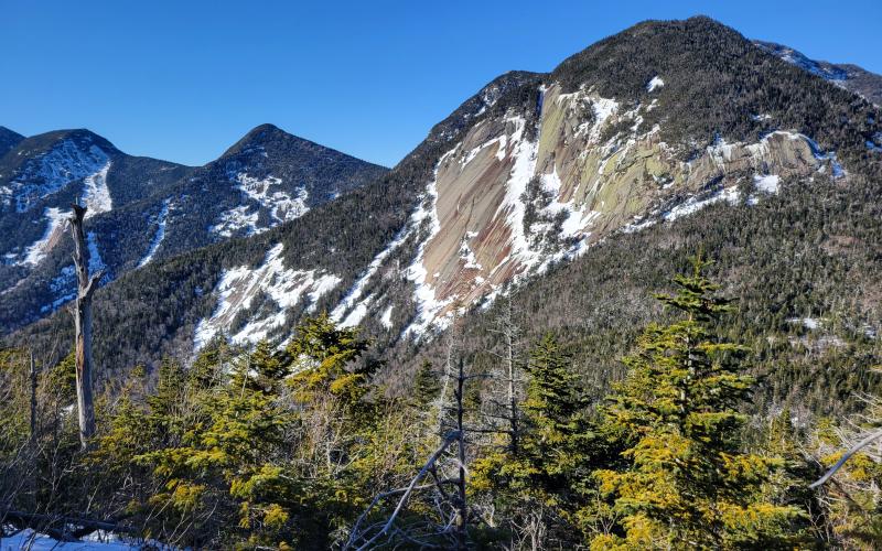 The view of mountains with large rock slabs with some snow on them.