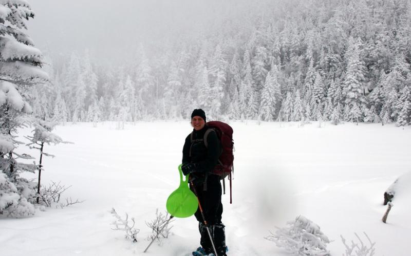 A hiker standing by a frozen pond