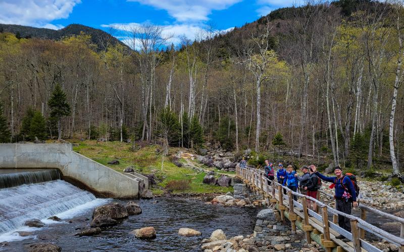 A bunch of hikers standing on a long, wooden bridge