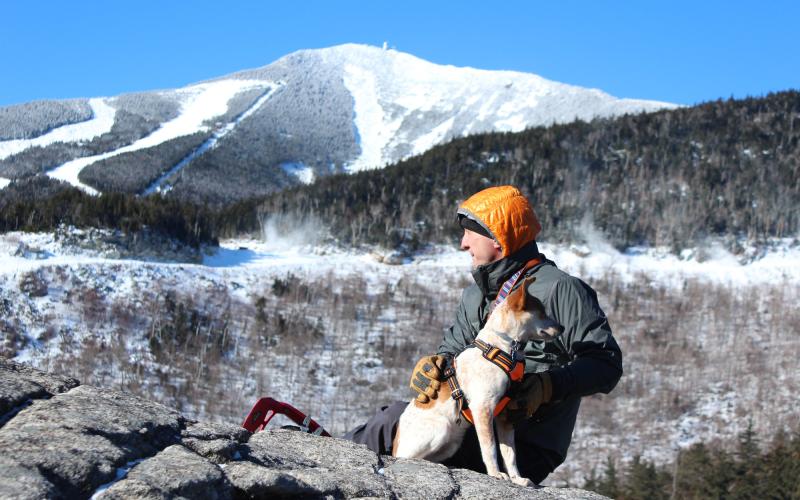 A hiker with his dog on a wintry summit