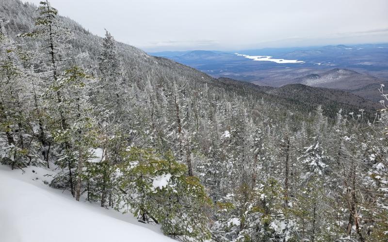 A snowy view down towards a long lake