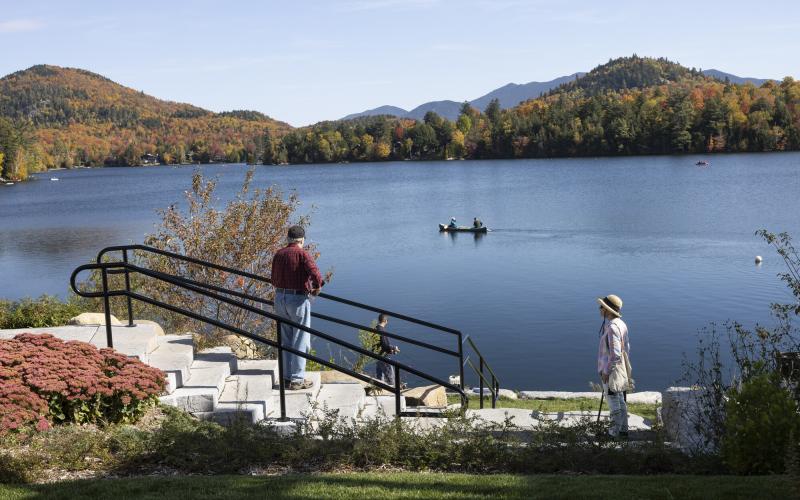 Two people watch a paddler out on a lake