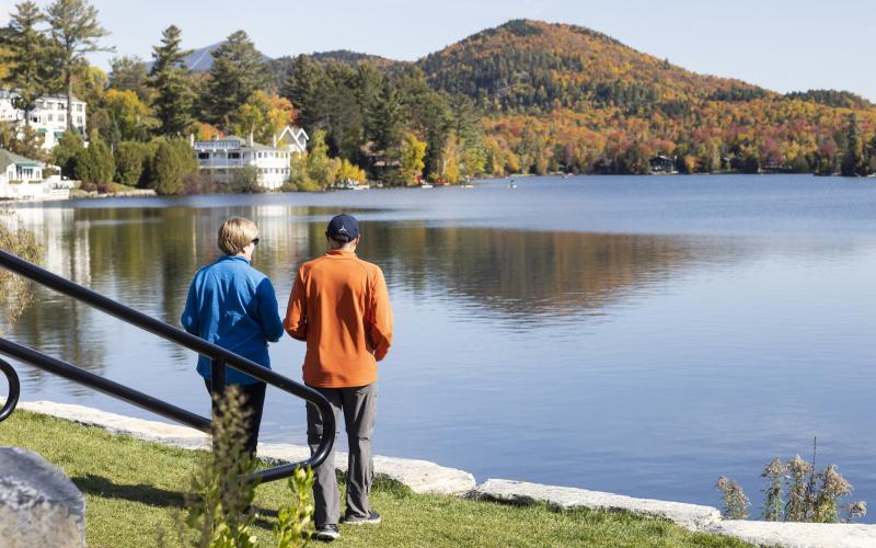 Two people look at the view of a mountain across a lake