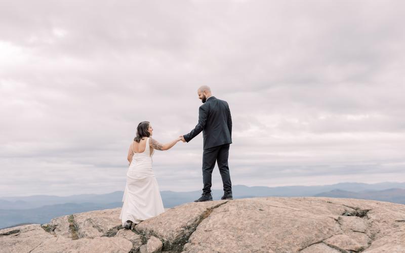 Bride and groom laugh atop a rocky knoll