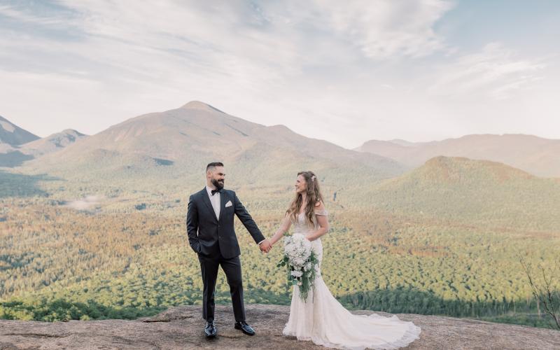 Bride and Groom gaze at each other while holding hands with mountain views in the background