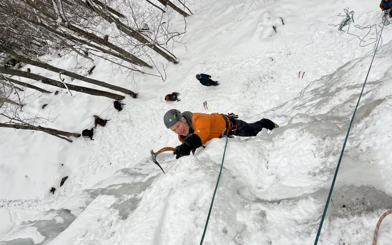 Man with an ice pick ascends an ice wall