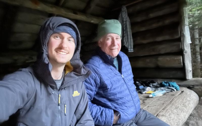 Smiling men sit in a lean to