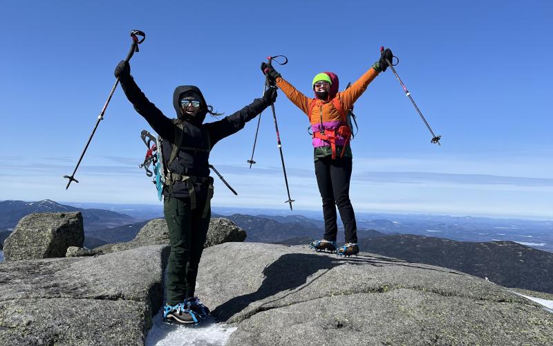 Mountaineers throw their hands in the air in celebration after ascent