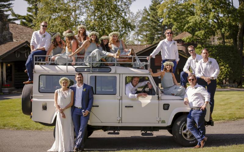 Wedding party posed around an antique safari truck