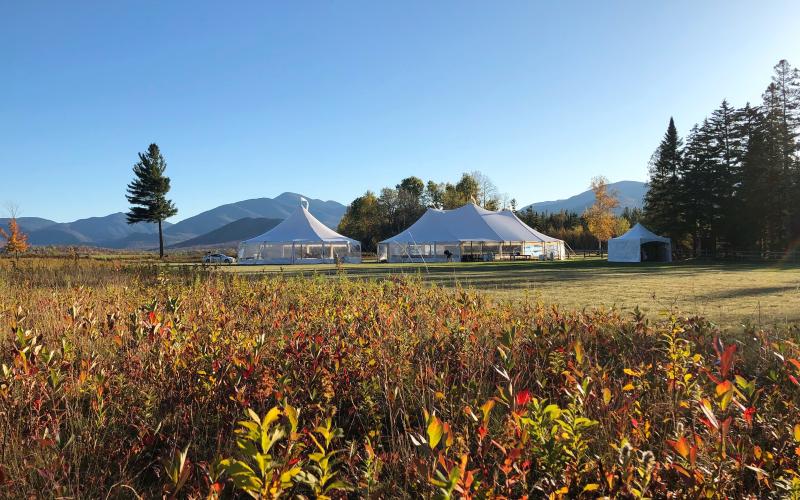 Fall color sweeps through the meadow offsetting the large white tents of the wedding celebration