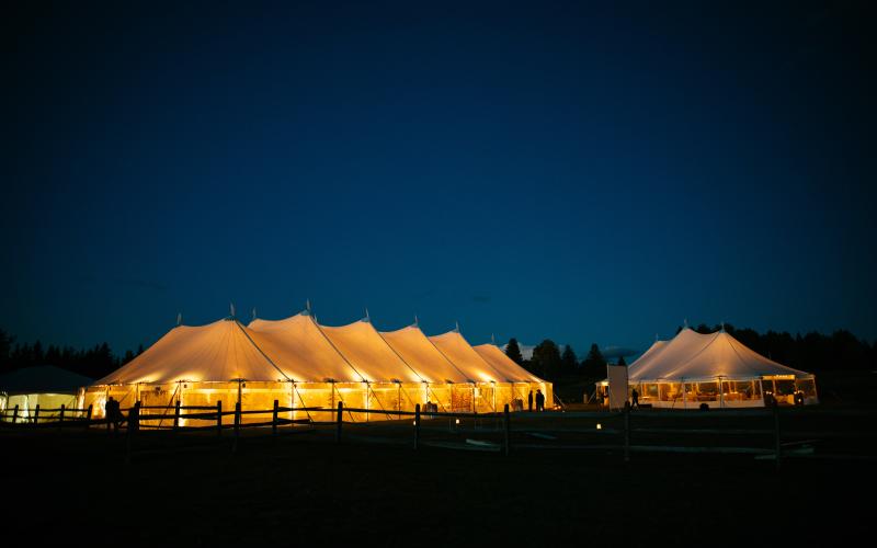 Illuminated tents with a golden glow against the deep blue ski