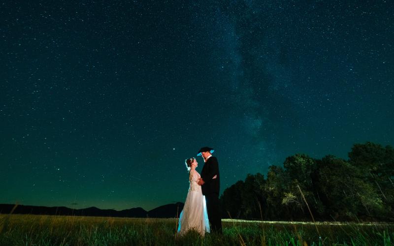 Bride and groom embrace below the milkyway