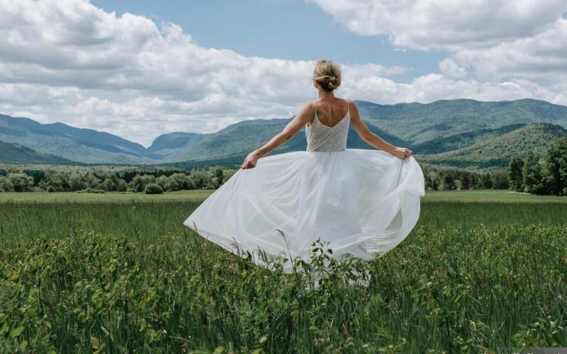 A bride fans out her dress and takes in the majestic view of the high peaks